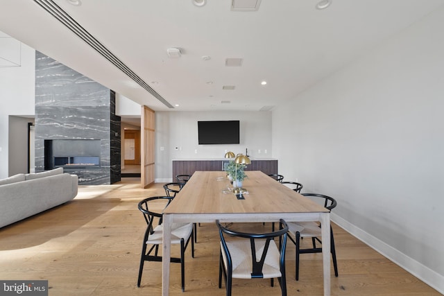 dining room with a high end fireplace and light hardwood / wood-style flooring