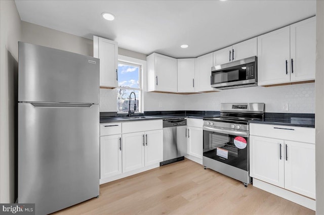 kitchen featuring stainless steel appliances, sink, white cabinets, and light hardwood / wood-style flooring