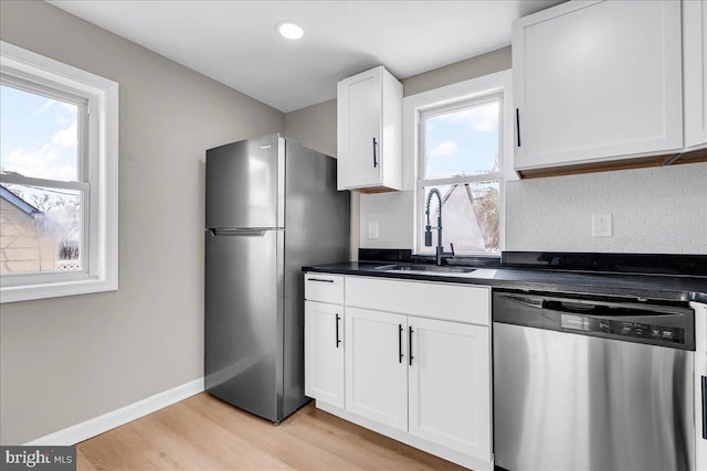 kitchen featuring sink, white cabinetry, light wood-type flooring, appliances with stainless steel finishes, and a wealth of natural light