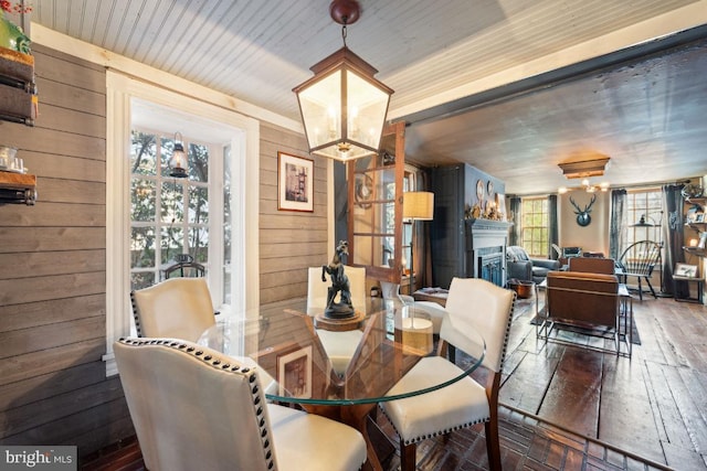 dining room with an inviting chandelier, dark hardwood / wood-style floors, and wood walls