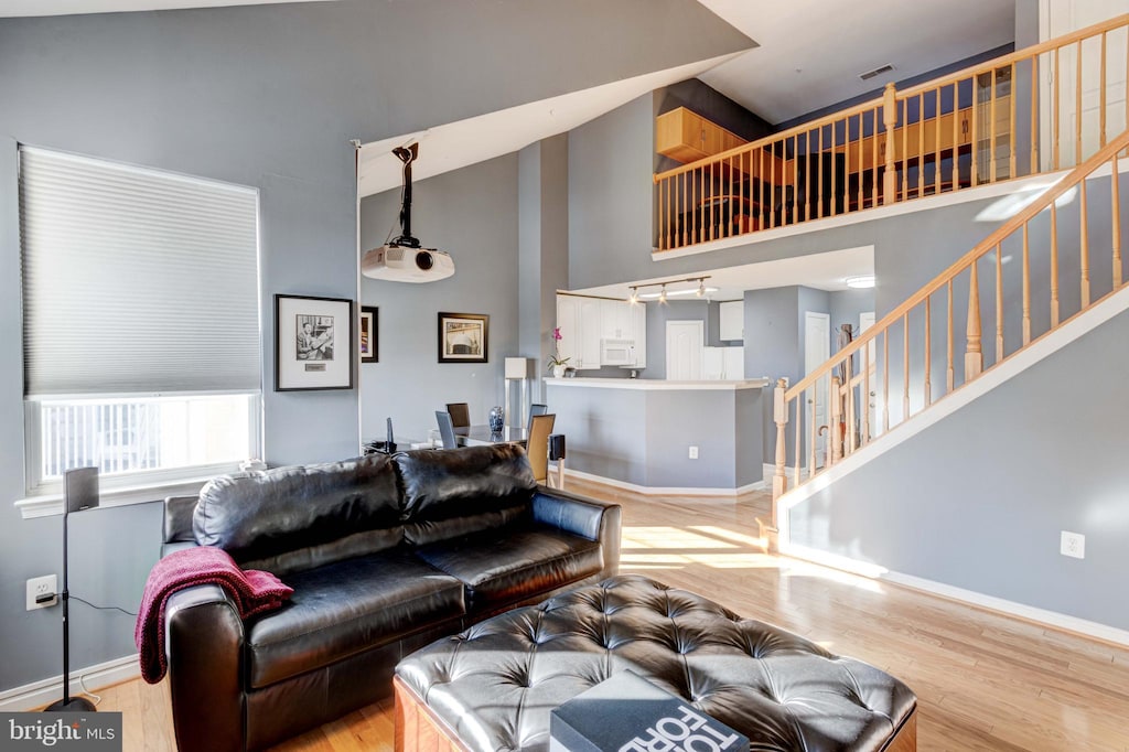 living room featuring wood-type flooring and high vaulted ceiling