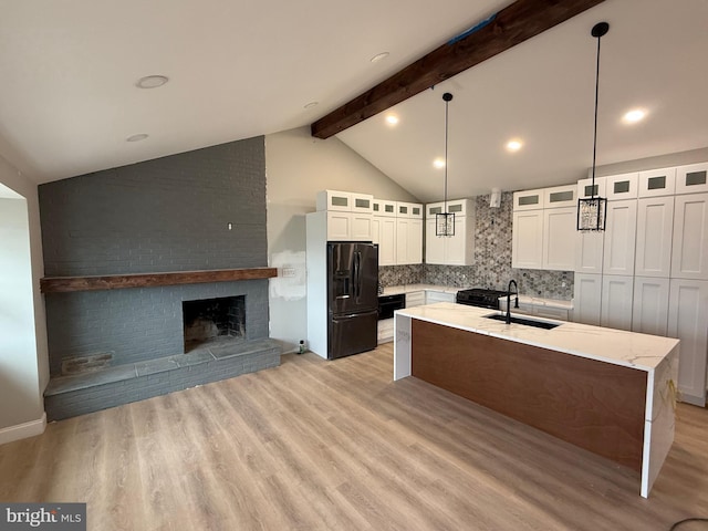 kitchen with white cabinetry, an island with sink, pendant lighting, and black fridge with ice dispenser