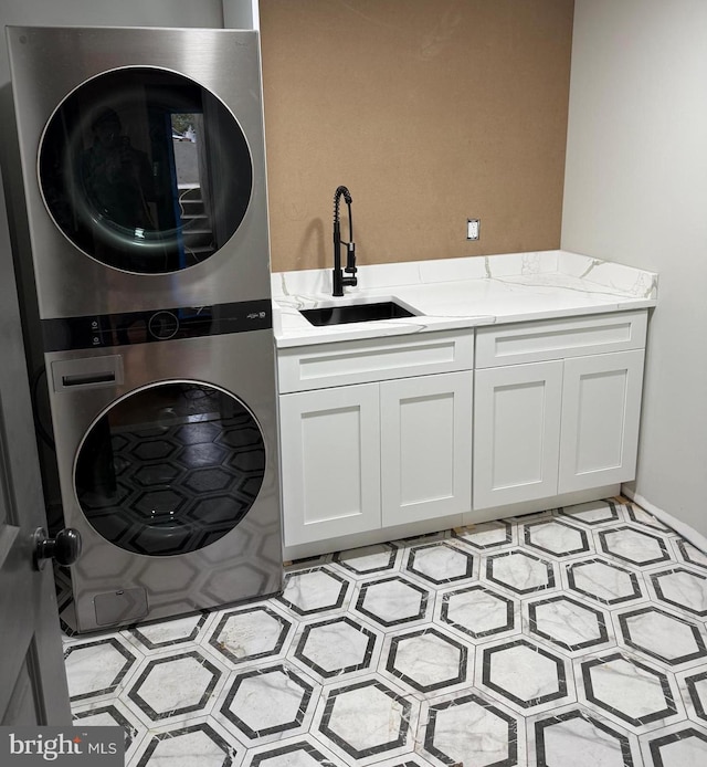 clothes washing area with stacked washer and dryer, sink, and cabinets