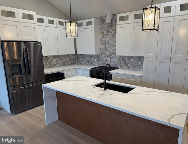 kitchen with pendant lighting, sink, an island with sink, white cabinets, and stainless steel fridge with ice dispenser