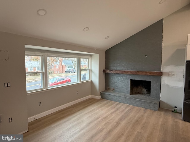 unfurnished living room featuring lofted ceiling, a fireplace, and light hardwood / wood-style flooring