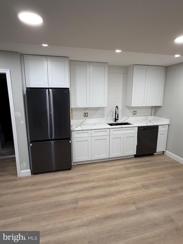 kitchen with sink, light hardwood / wood-style flooring, white cabinets, and black appliances