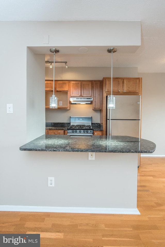 kitchen with appliances with stainless steel finishes, decorative light fixtures, and kitchen peninsula