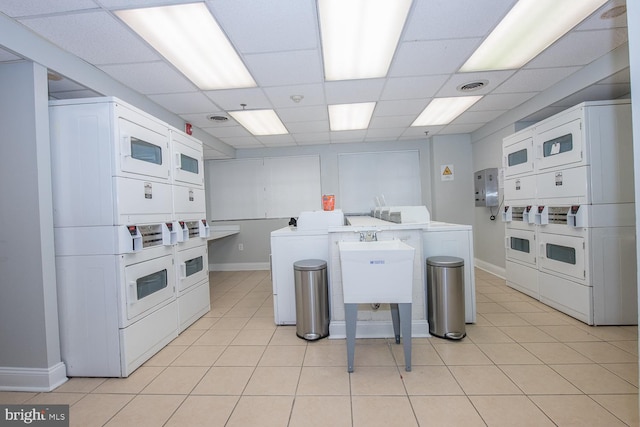 laundry area with stacked washing maching and dryer, sink, light tile patterned floors, and washing machine and dryer