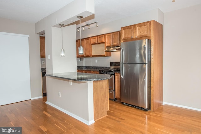 kitchen featuring decorative light fixtures, a kitchen breakfast bar, kitchen peninsula, stainless steel appliances, and light hardwood / wood-style floors