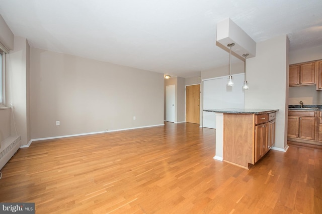 kitchen featuring pendant lighting, sink, light hardwood / wood-style flooring, a baseboard radiator, and kitchen peninsula