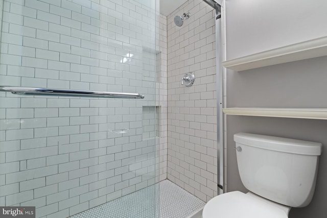 bathroom with a shower with shower door and toilet