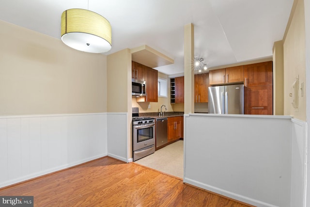 kitchen featuring appliances with stainless steel finishes, sink, and light wood-type flooring