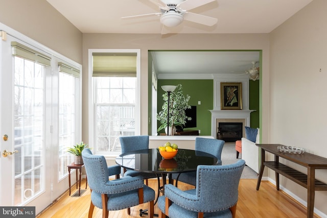 sunroom featuring a ceiling fan and a glass covered fireplace