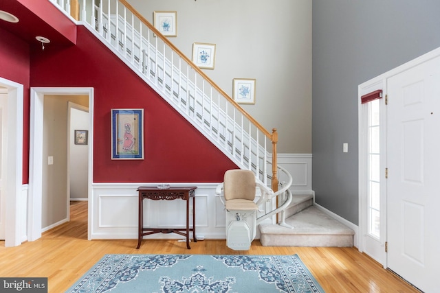 entryway featuring a wainscoted wall, stairway, a wealth of natural light, and wood finished floors