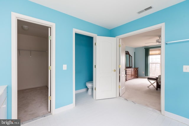 carpeted bedroom with baseboards, visible vents, a walk in closet, and a closet