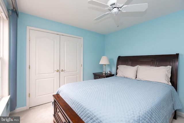 bedroom with a ceiling fan, a closet, light carpet, and baseboards