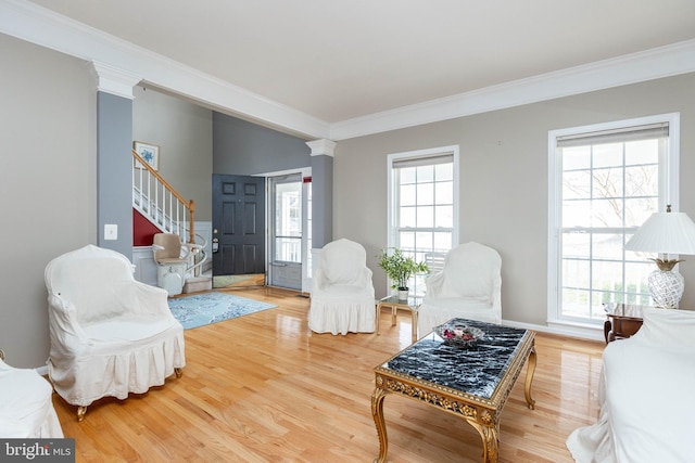 living room with stairs, light wood-style flooring, and crown molding