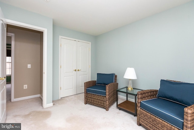 sitting room featuring baseboards and light colored carpet