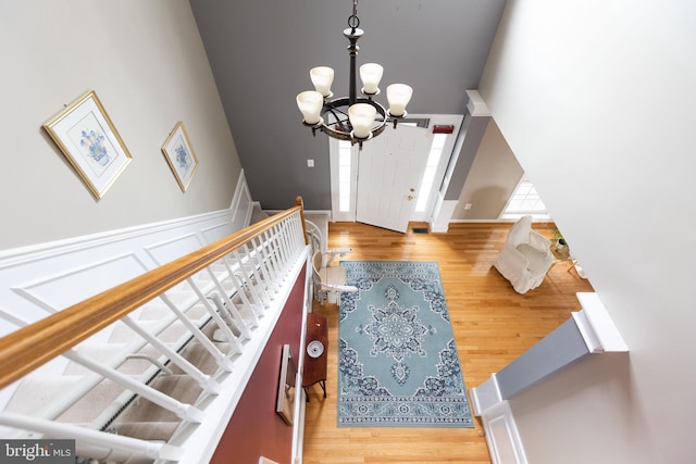 foyer featuring a wainscoted wall, a notable chandelier, stairway, and wood finished floors