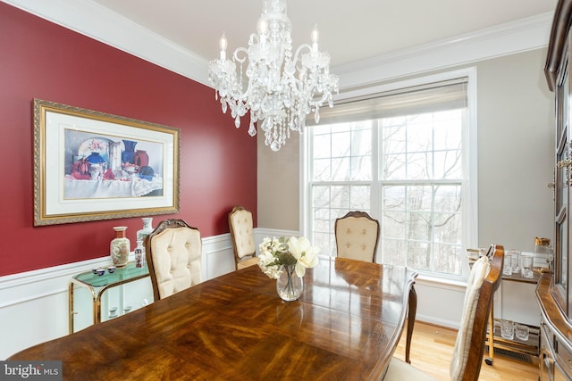 dining room with a wealth of natural light, wainscoting, crown molding, and a notable chandelier