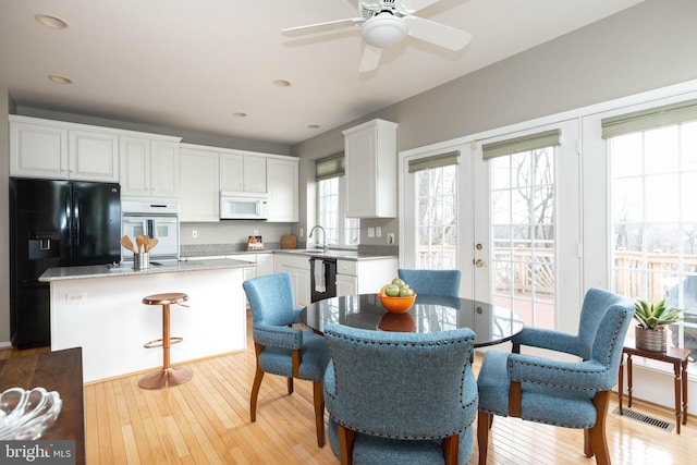 dining area featuring light wood-style floors, french doors, visible vents, and a ceiling fan