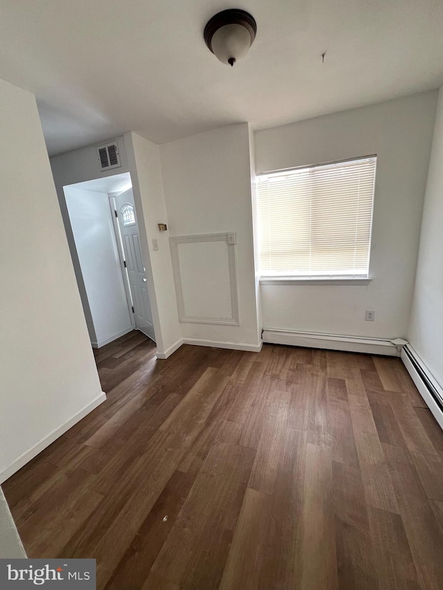 spare room featuring dark wood-type flooring and baseboard heating