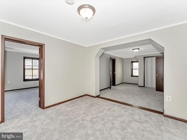 carpeted spare room with ornamental molding and plenty of natural light