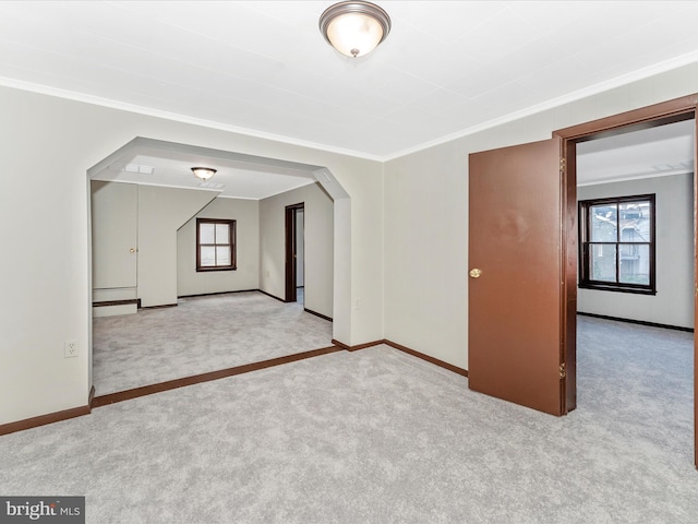 carpeted empty room featuring crown molding and plenty of natural light