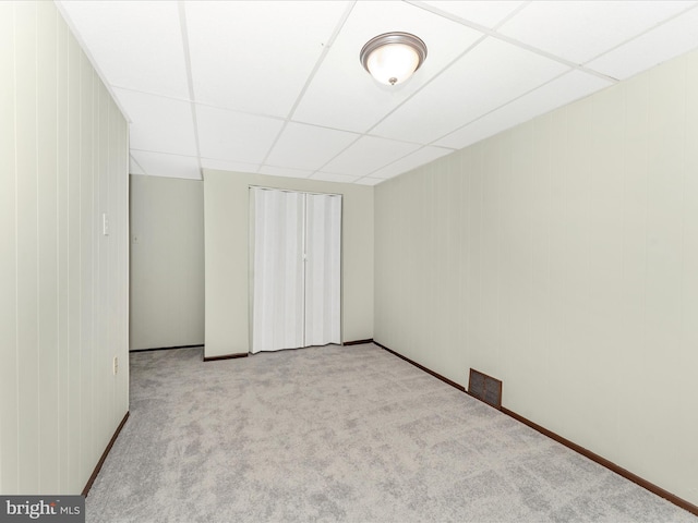 spare room with a paneled ceiling and light colored carpet