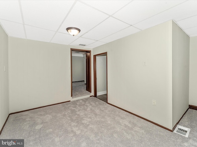 carpeted spare room featuring a drop ceiling