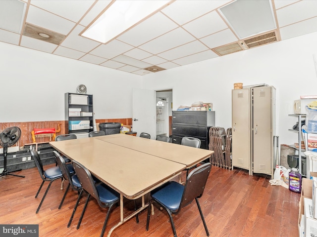 dining area with wooden walls, dark hardwood / wood-style flooring, and a drop ceiling