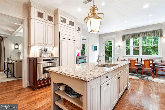 kitchen with stainless steel oven, an island with sink, coffered ceiling, and sink