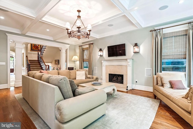 living room featuring coffered ceiling, light hardwood / wood-style flooring, decorative columns, and beamed ceiling