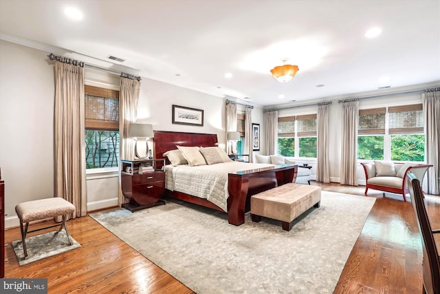 bedroom with multiple windows, crown molding, and wood-type flooring