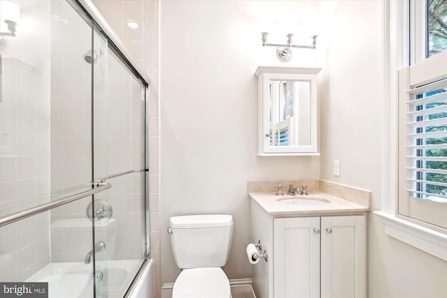 full bathroom featuring enclosed tub / shower combo, vanity, and toilet