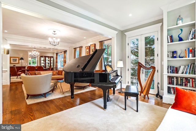 sitting room with a notable chandelier, hardwood / wood-style flooring, built in shelves, and a healthy amount of sunlight