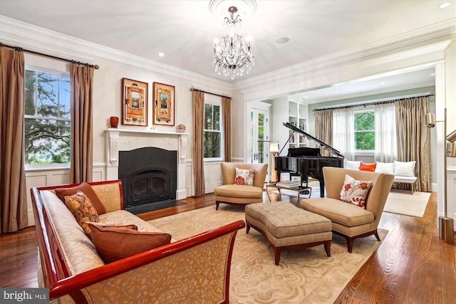 living area featuring crown molding, an inviting chandelier, a fireplace, and hardwood / wood-style floors