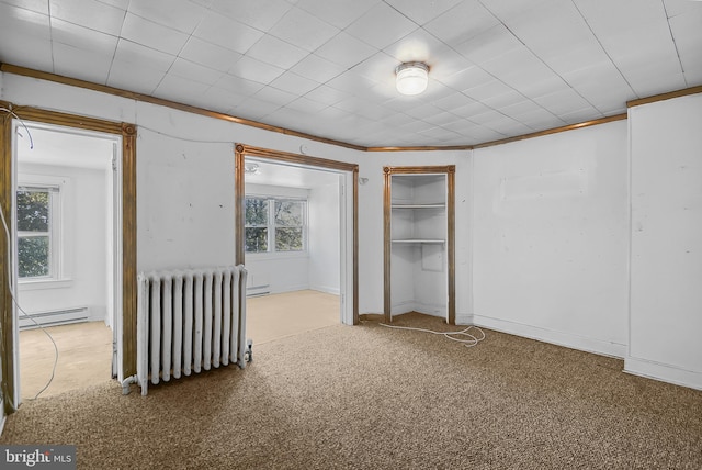 unfurnished bedroom featuring ornamental molding, radiator heating unit, light colored carpet, and baseboard heating