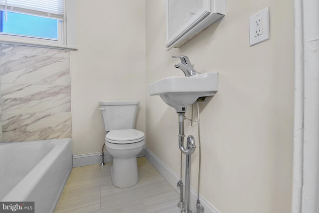 bathroom with a washtub, tile patterned floors, and toilet