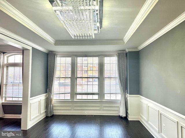 unfurnished room featuring a notable chandelier, crown molding, dark wood-type flooring, and a raised ceiling