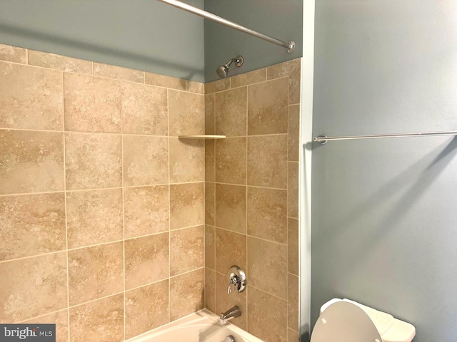 bathroom featuring toilet and tiled shower / bath