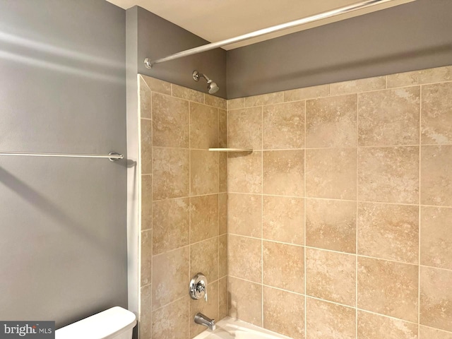 bathroom featuring tiled shower / bath combo and toilet