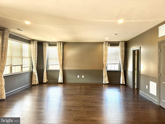 empty room featuring dark wood-type flooring and a healthy amount of sunlight