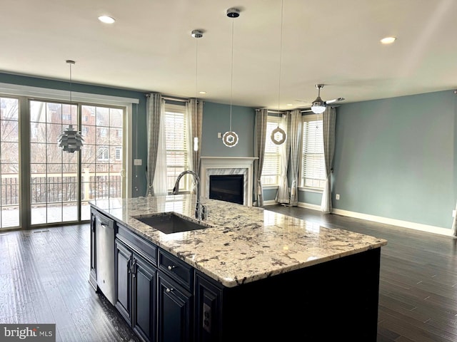 kitchen featuring pendant lighting, a fireplace, dishwasher, sink, and a center island with sink