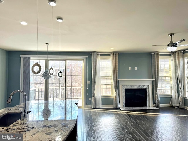 interior space featuring a wealth of natural light, sink, dark hardwood / wood-style flooring, a premium fireplace, and light stone countertops