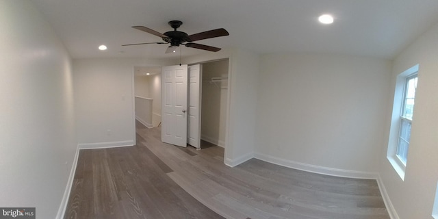 unfurnished bedroom featuring multiple windows, hardwood / wood-style flooring, a closet, and ceiling fan