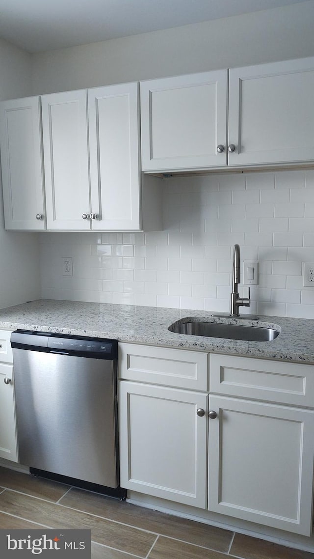 kitchen with sink, tasteful backsplash, dishwasher, light stone countertops, and white cabinets