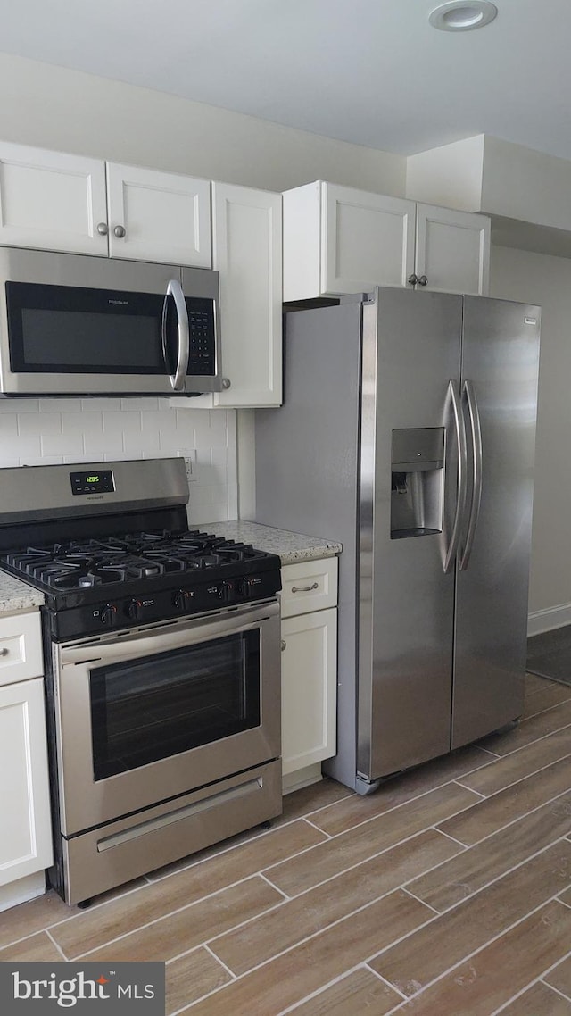 kitchen with white cabinetry, hardwood / wood-style flooring, and appliances with stainless steel finishes