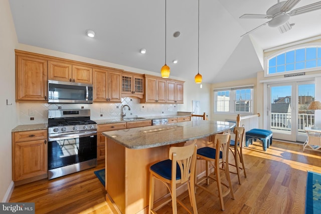 kitchen featuring dark wood-type flooring, sink, decorative light fixtures, a center island, and stainless steel appliances