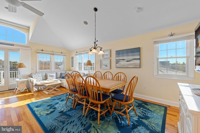 dining room featuring a notable chandelier, a wealth of natural light, vaulted ceiling, and light wood-type flooring